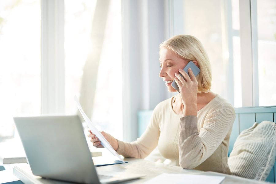 Mitarbeiterin arbeitet am Laptop und telefoniert im Büro