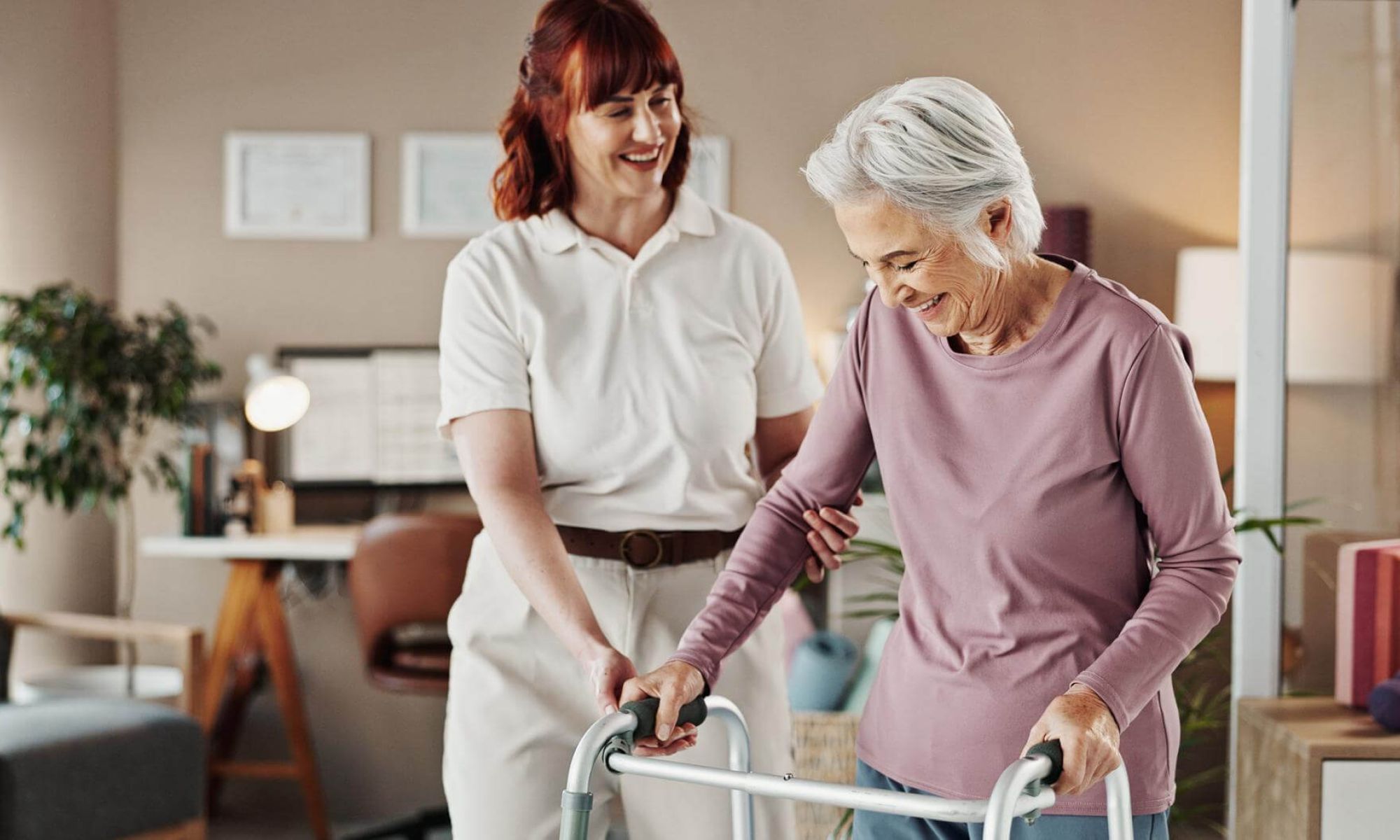 Pflegekraft begleitet eine Seniorin mit Rollator im Wohnbereich