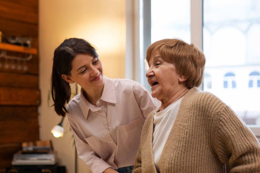 Mitarbeiterin spricht mit einer Seniorin im Wohnbereich