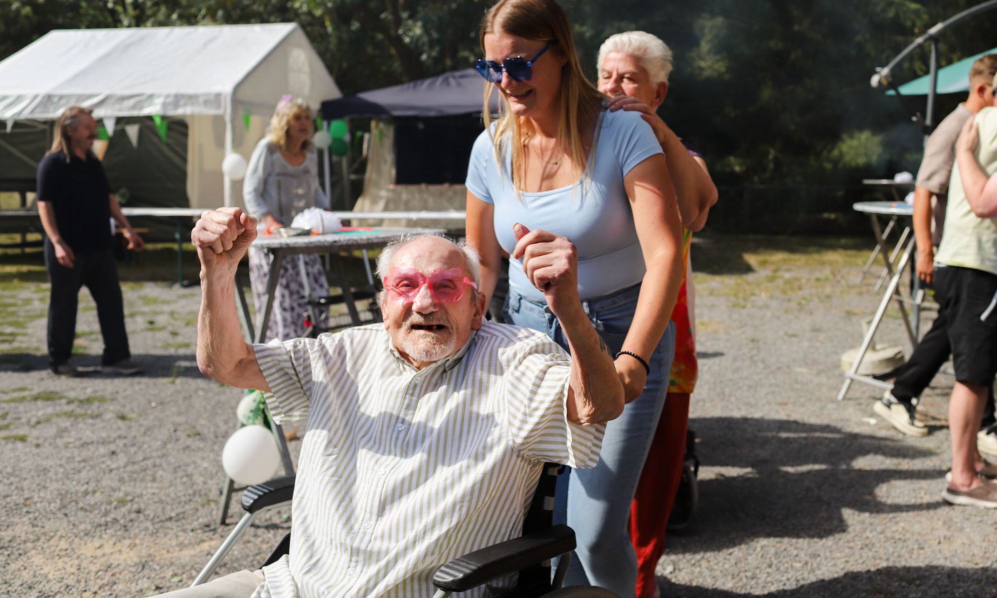 Betreuungskraft begleitet eine Seniorin im Rollstuhl im Park